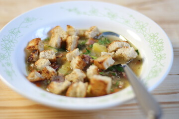 Pea soup with smoked ribs, potato, parsley, toast, spoon  in rustic bowl on wooden table 