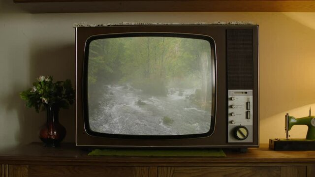 An old analog TV showing a River in the mountains on the screen.