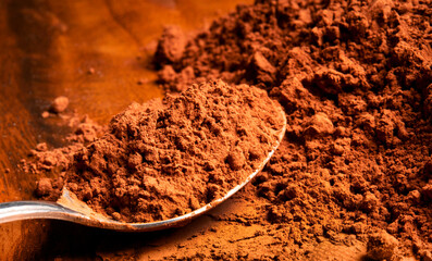 cocoa or cacao powder with old spoon lying on old wood like food in vintage style and backround
