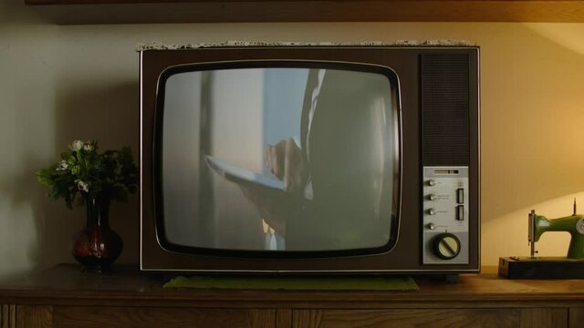 An old retro television showing a modern scene of a woman using a tablet.
