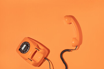 Old phone on bright bold orange background. Retro aesthetic style. Trendy minimal flat lay. Spring...