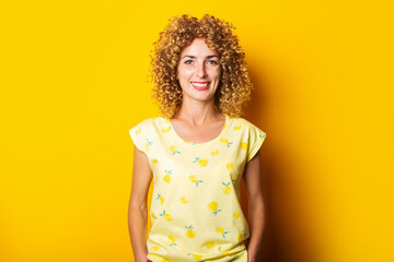 beautiful affable curly young woman on a bright yellow background