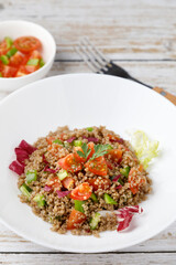 Healthy rustic quinoa salad with vegetables on a white wood table