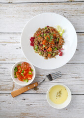 Healthy rustic quinoa salad with vegetables on a white wood table