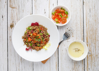Healthy rustic quinoa salad with vegetables on a white wood table