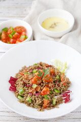 Healthy rustic quinoa salad with vegetables on a white wood table