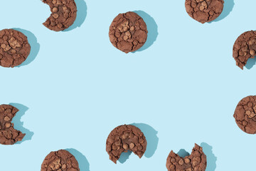 Creative pattern or frame made with chocolate chip cookies on pastel blue background. Happy sweet fun life idea. Trendy food or dessert concept. Spring or summer layout.
