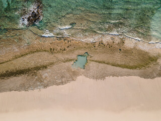 Fototapeta na wymiar Sandy and rocky beach shore background top view aerial shot