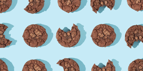 Creative pattern made with chocolate chip cookies on pastel blue background. Happy sweet optimistic life idea. Fun food or dessert concept. Spring or summer layout.