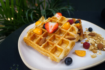 Fresh homemade waffles with blueberries and Strawberry for breakfast on black table.
