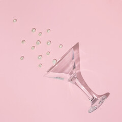 Creative layout with martini cocktail glass and white pearls on pastel pink background. 80s or 90s...