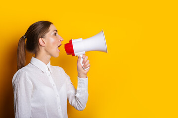 Young woman in a white shirt shouts into a megaphone on a yellow background. Concept for hiring, listing, help wanted. Banner