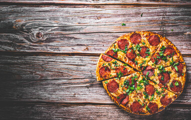 Fototapeta na wymiar Pepperoni Pizza with Mozzarella cheese, salami, Tomato sauce, pepper, Spices and Fresh basil. Italian pizza on wooden table background
