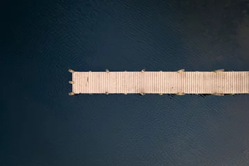 Fotobehang Pier Birds eye view of wooden jetty leading out over lake taken with drone.  © _Danoz