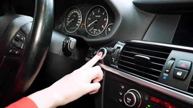 girl pressing the start button of the car close-up