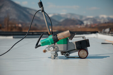 Automatic welder hot-air tools welds synthetic membranes on roof.