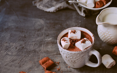 Hot chocolate and marshmallows. Hot Cocoa in a white cup. Dark background. Copy space. Steam from a cup.