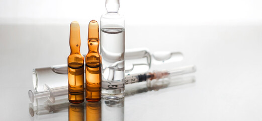 Medical ampoules on a glossy background.Photos on the topic of medicine, vaccination, injections,...