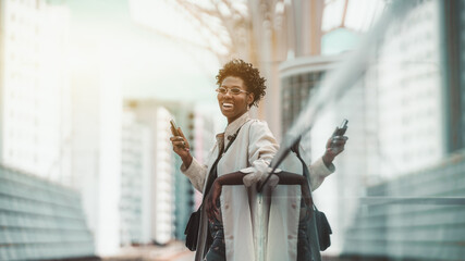 Cheerful laughing young fancy African female is leaning against a reflecting glass surface while...