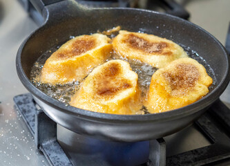 Four torrijas (spanish french toasts) being fried on a stove pan in a home kitchen. Typical food for holy week made with bread, egg, milk, cinnamon and sugar. Dessert and sweet dish.
