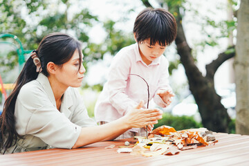葉っぱで遊ぶお母さんと息子