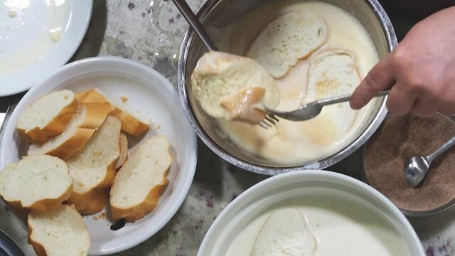Top view of a woman preparing torrijas (french toast) a typical spanish dish for holy week. Soaking bread in milk and egg and fried with cinnamon and sugar. Homemade cooking