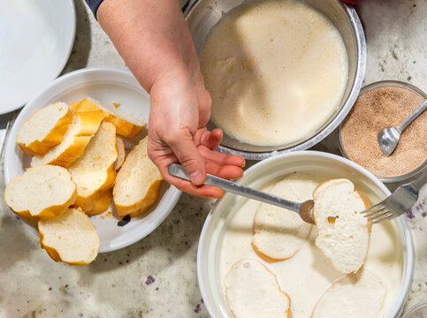 Top view of a woman preparing torrijas (french toast) a typical spanish dish for holy week. Soaking bread in milk and egg and fried with cinnamon and sugar.
