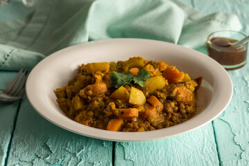 Lentil and vegetable stew on rustic table with chutney