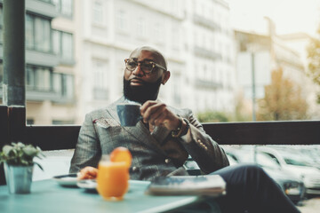 The portrait of a handsome stylish wealthy African guy with a beautiful black beard, in glasses,...