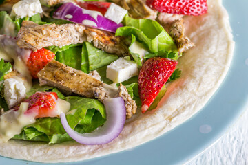 Tortilla wrap salad with chicken, cheese and strawberries close up photo