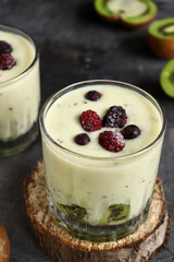 Yogurt with berry and kiwi in a glass. Fruit and berry smoothie. Milkshake with kiwi, raspberry, blueberry and banana Healthy food. Dark background. Copy space.