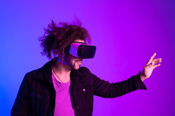 African american man long afro hair with vr glass, playing video games with virtual reality headset, trying to touch something with his hand. pink blue background