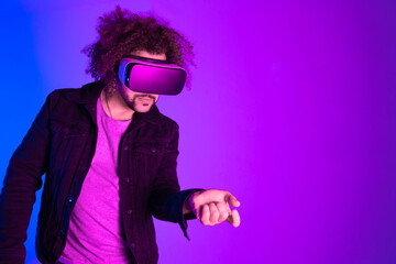 African american man is wearing virtual reality headsets. Neon light studio portrait. Virtual reality, simulation, game and future technology concept.