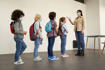 Protective measures. Full length shot of young female teacher screening kids with digital...