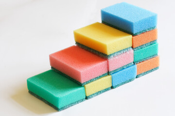 Ten multi-colored, readable dishwashing sponges lie on a white surface. Ladder. The concept of improving the quality of cleaning