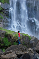 A boy standing next to a waterfall