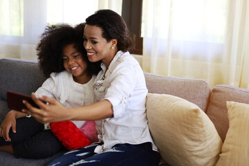 American kid girl smile portrait and selfie photo with mother at home.