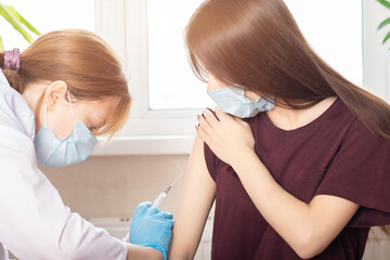 Vaccination of adolescents in medical clinics, schools, a doctor giving an injection to a girl in a...