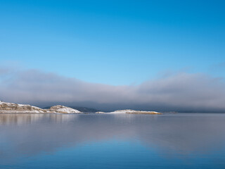 Bare islands with snow and purple cloud reflections in the sea.. Desolate feeling. Shot in Sweden, Scandinavia