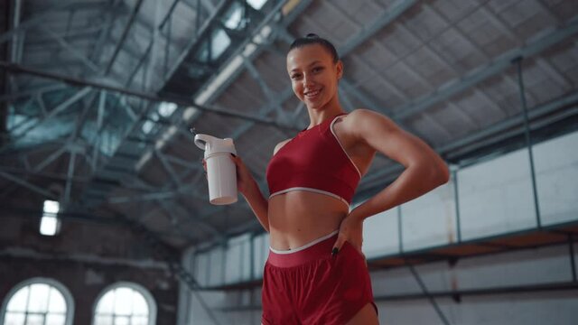 Beautiful woman  drinks protein shake while exercising in the fitness room. Sports and technology concept. Lifestyle and health theme.