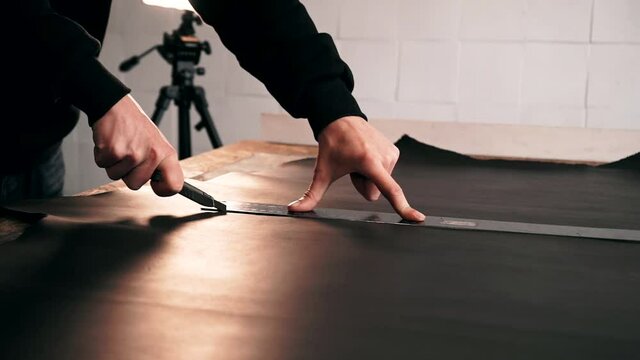 the master makes a cut for sewing a leather bag