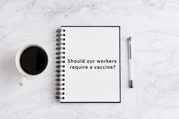 Notebook on desk written should our workers require vaccine