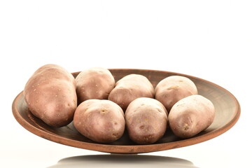 Several unpeeled raw potatoes with a plate, close-up, isolated on white.