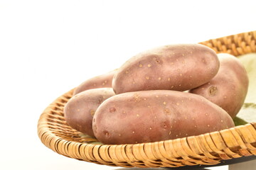 Several unpeeled raw potatoes with a plate, close-up, isolated on white.