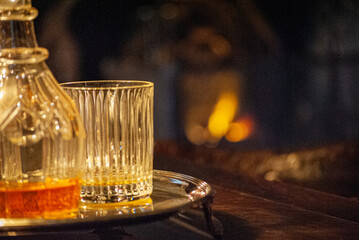 glass of whisky on table and fireplace on bavkground