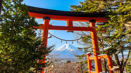 Distant view on Mt Fuji,framed in between orange Torri gate, leading to Chureito Pagoda in Japan, on a clear, wintery day. The top parts of the volcano are covered with a layer of snow. Holly mountain