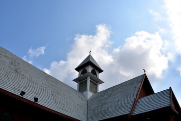 Church Roof with a cross. Church building roof with holy cross. Cloudy moody blue sky background. Minimal architecture design and detail. Exterior design and detail. Abstract architecture.