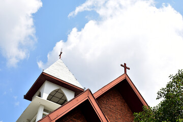 Church Roof with a cross. Church building roof with holy cross. Cloudy moody blue sky background. Minimal architecture design and detail. Exterior design and detail. Abstract architecture.