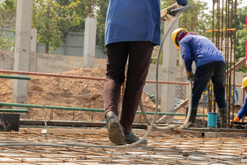 Workers put jeans on their feet holding concrete vibrators in their hands on rebar for pouring concrete in construction sites, columnar backgrounds and building conditions during construction.