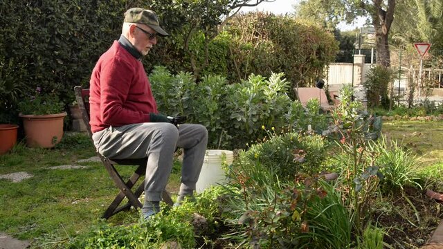 uomo anziano in isolamento cura il suo giardino 